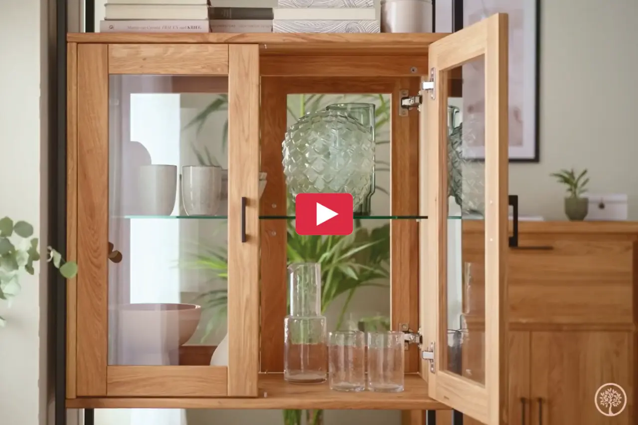 Offene Vitrine aus Massivholz mit Glastüren und Glasböden. Im Inneren stehen Gläser, Schalen und Dekoration. Hochwertige Wohnzimmermöbel im natürlichen Design für modernes Wohnen mit Stauraum.